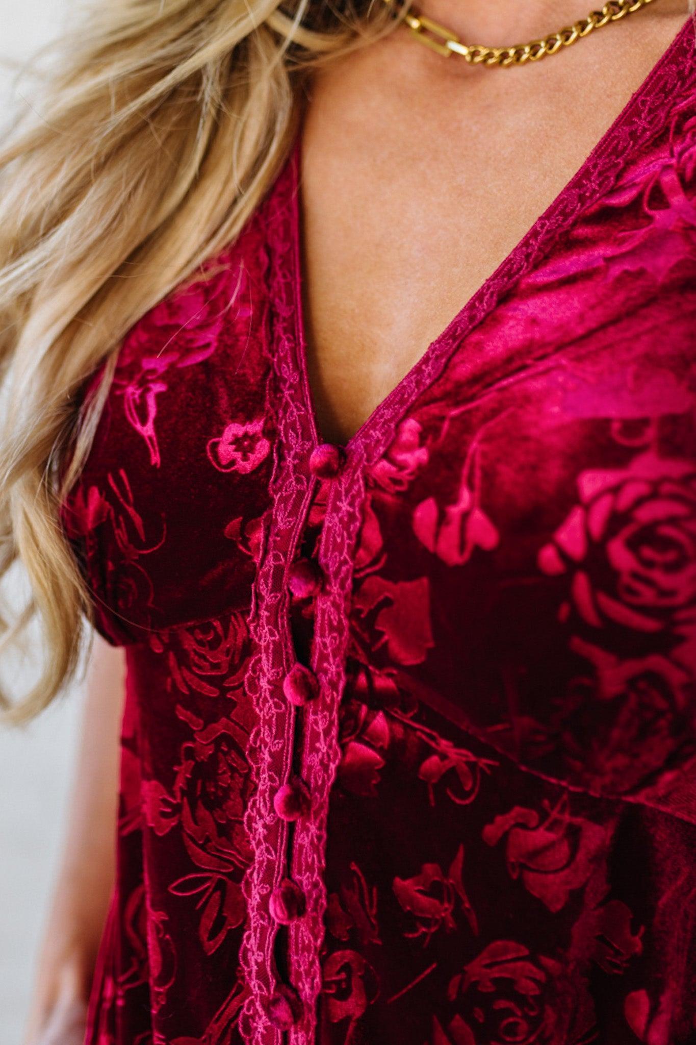 Close-up of a person wearing a red floral dress with a gold chain necklace.
