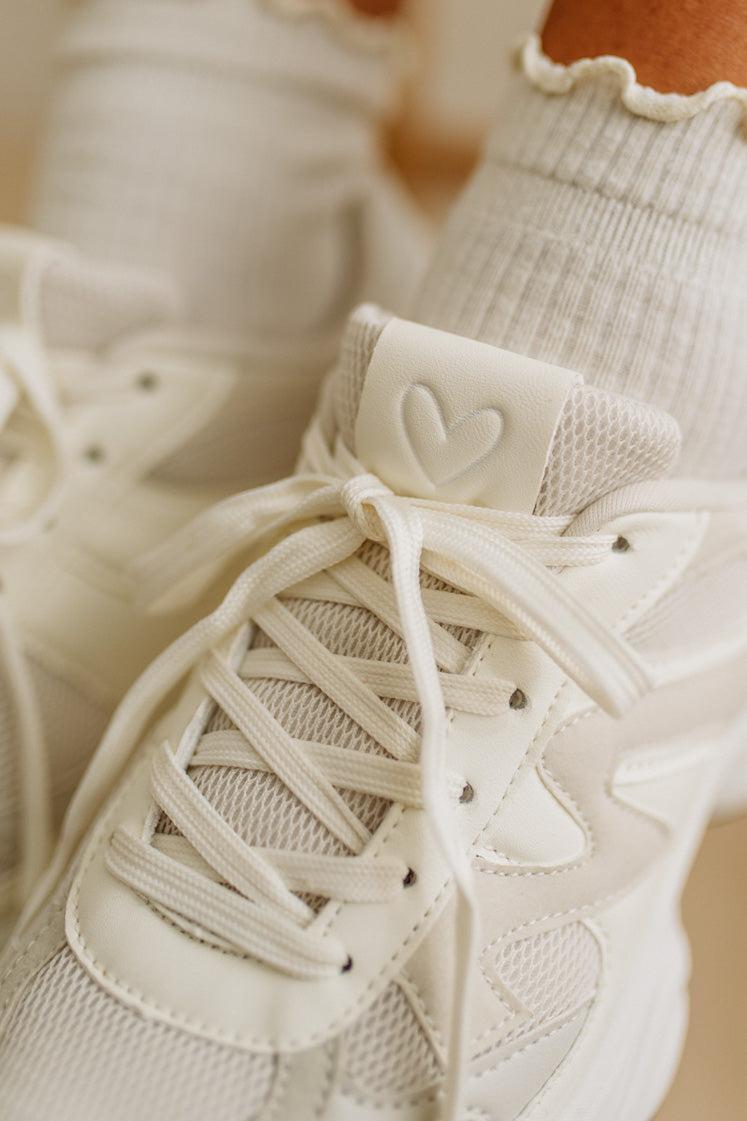 Close-up of beige sneakers with heart details on a blurred background