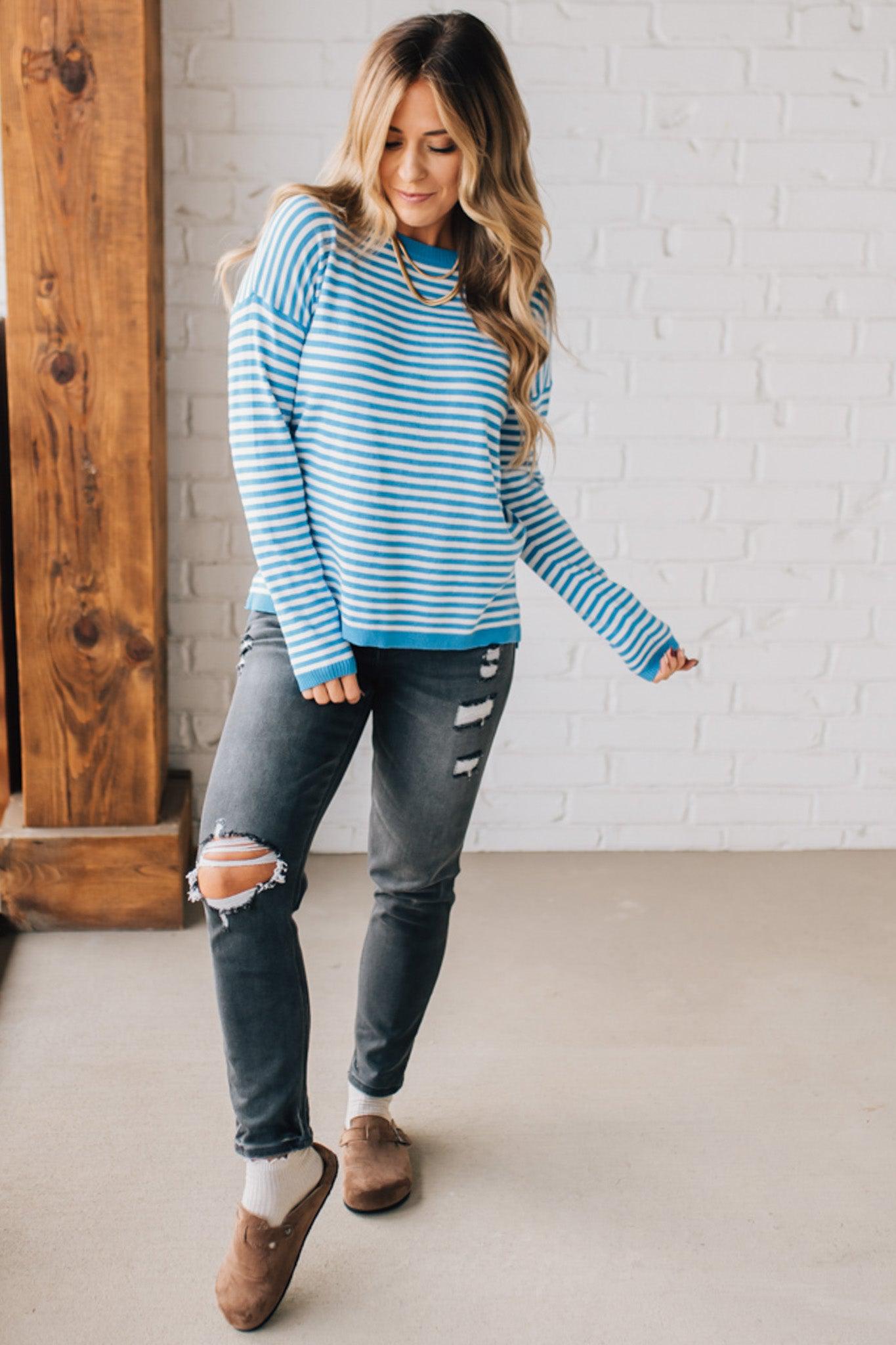 BLONDE WOMAN MODELING A LONG SLEEVE STRIPED LIGHTWEIGHT SWEATER WITH RIBBED SOLID COLORED NECKLINE AND SLEEVE CUFFS