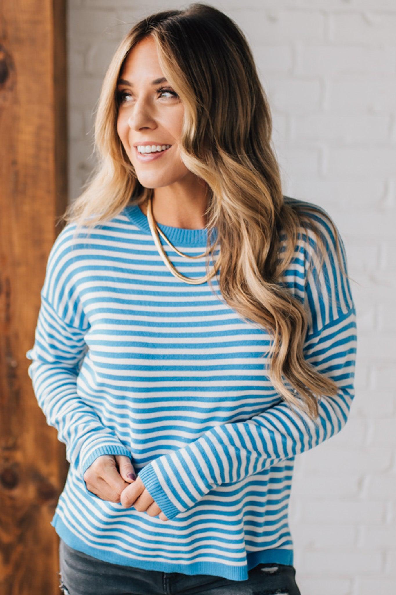 BLONDE WOMAN MODELING A LONG SLEEVE STRIPED LIGHTWEIGHT SWEATER WITH RIBBED SOLID COLORED NECKLINE AND SLEEVE CUFFS