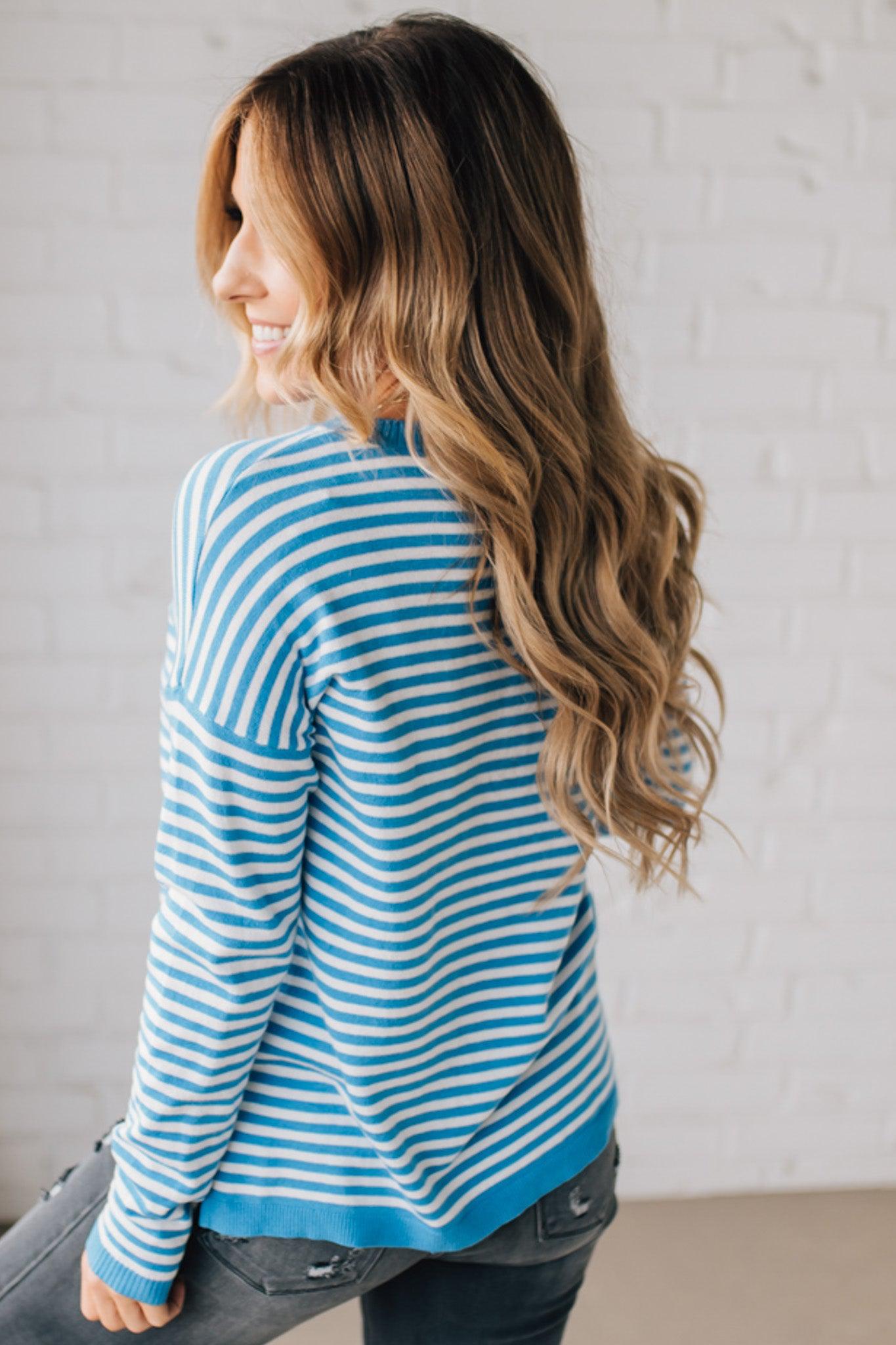 BLONDE WOMAN MODELING A LONG SLEEVE STRIPED LIGHTWEIGHT SWEATER WITH RIBBED SOLID COLORED NECKLINE AND SLEEVE CUFFS