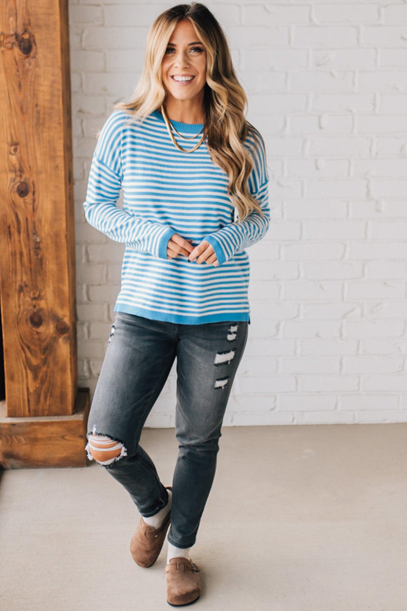 BLONDE WOMAN MODELING A LONG SLEEVE STRIPED LIGHTWEIGHT SWEATER WITH RIBBED SOLID COLORED NECKLINE AND SLEEVE CUFFS