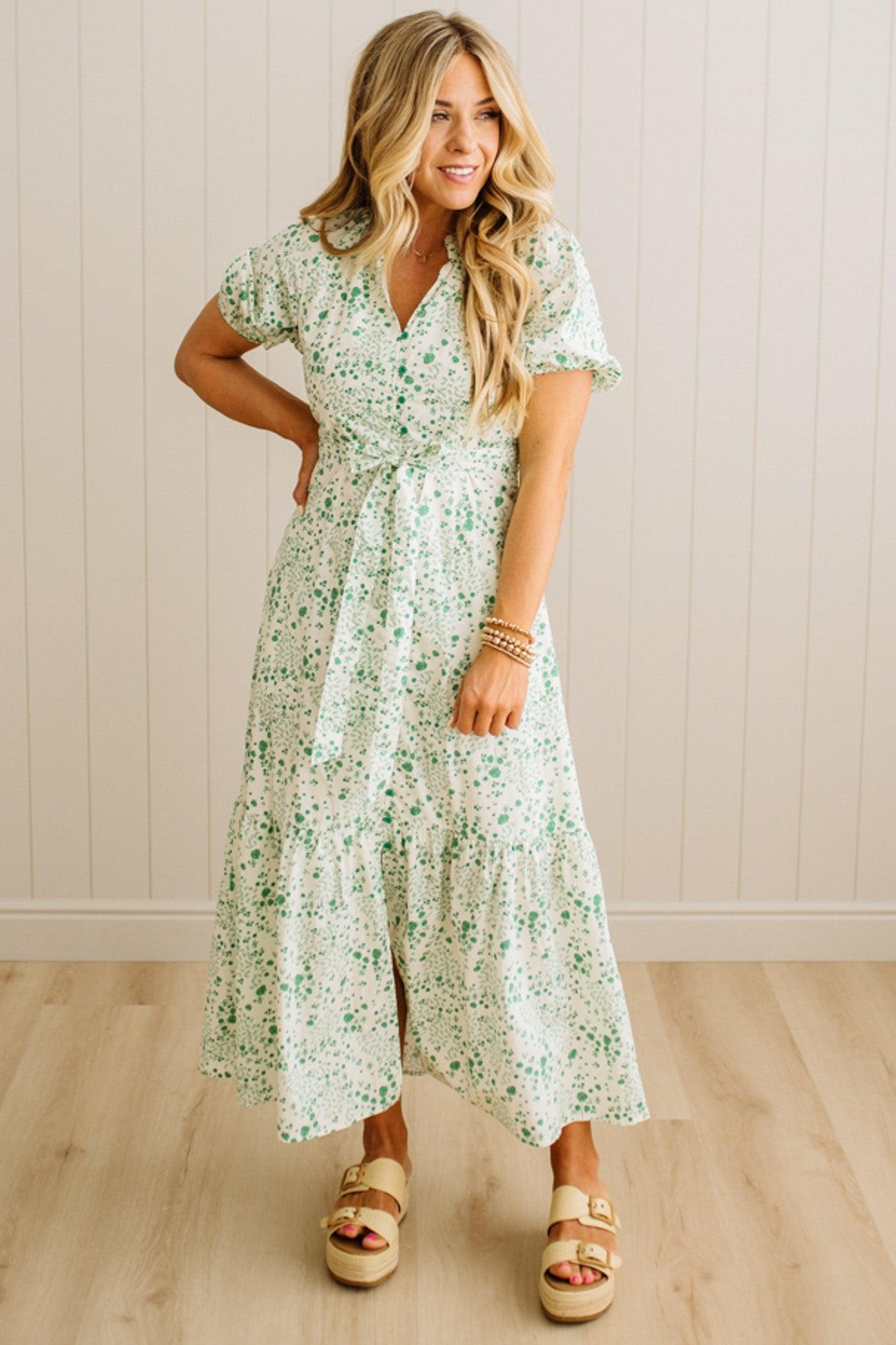 Woman wearing a floral dress standing against a plain background