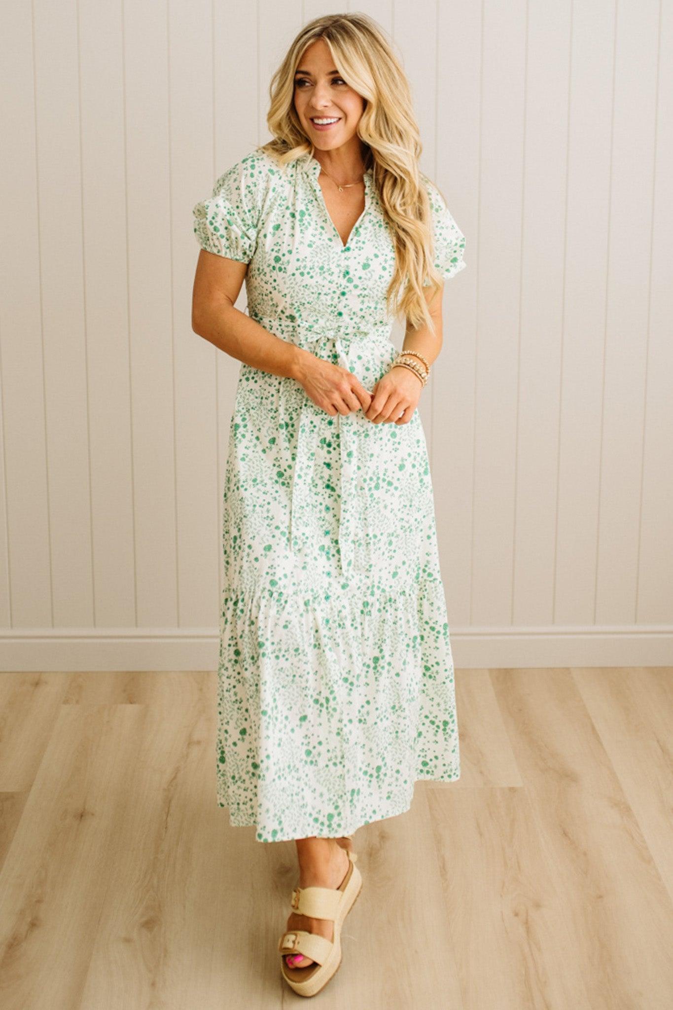 Woman wearing a floral dress standing against a plain background