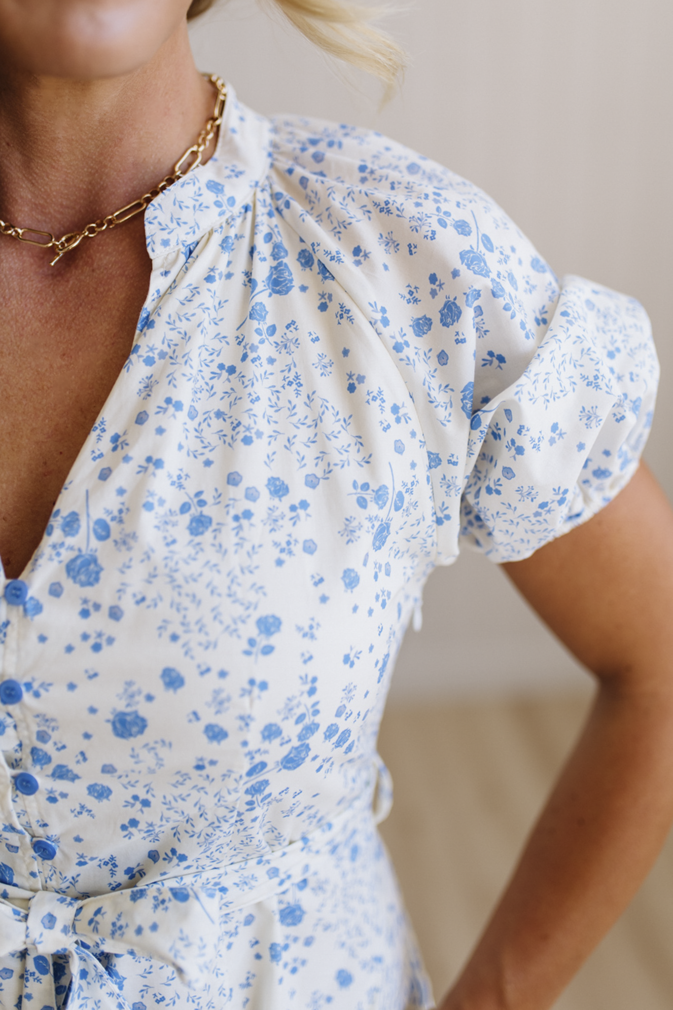 Woman wearing a floral dress with blue flowers on a neutral background