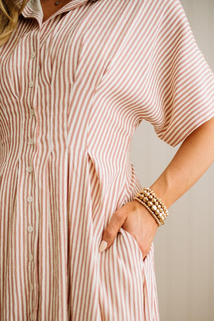 Person wearing a pink and white striped dress with a neutral background