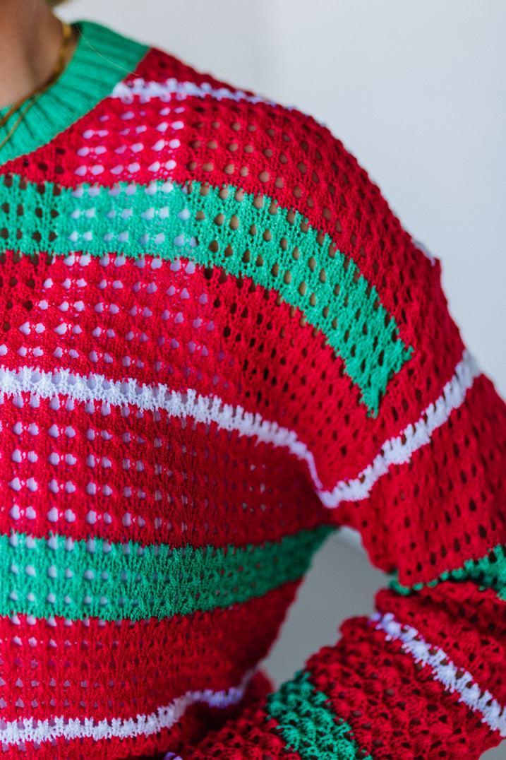 Close-up of a red, green, and white crocheted sweater with a plain background