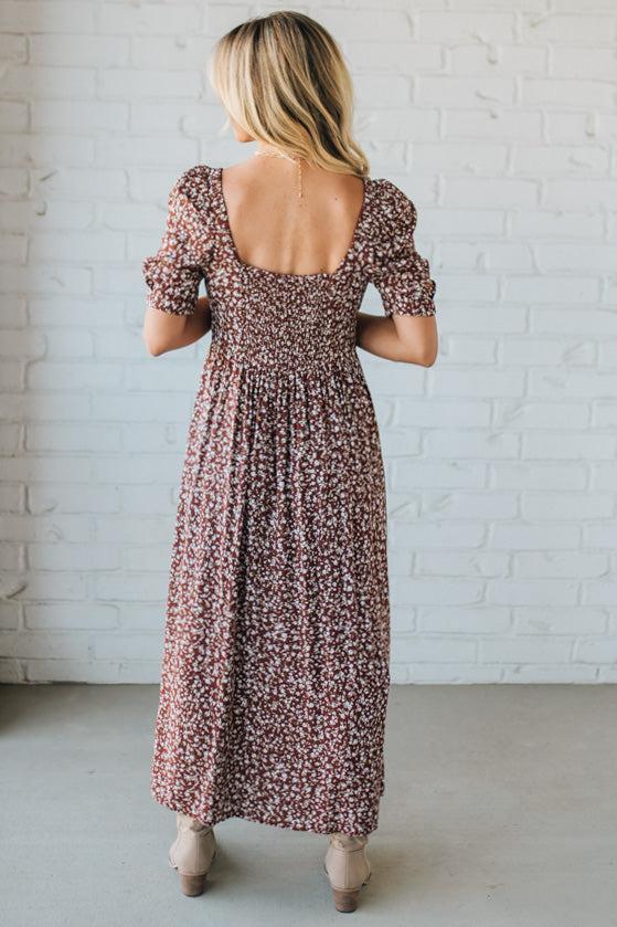 Woman wearing a floral dress with a white brick wall background