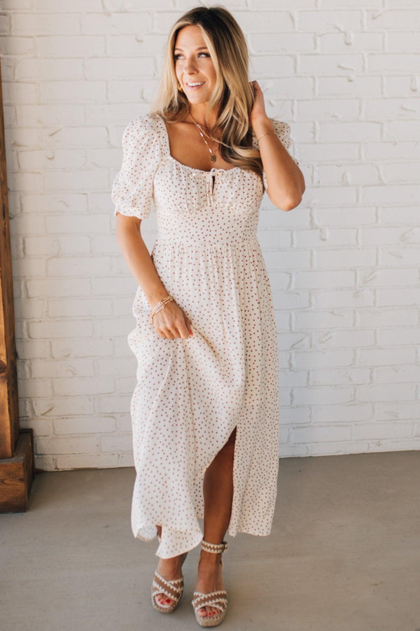 BLONDE WOMAN WEARING A CAMEL DOT PRINT CREAM MAXI DRESS W/ RUCHED BODICE & SLEEVES AND SIDE SLIT