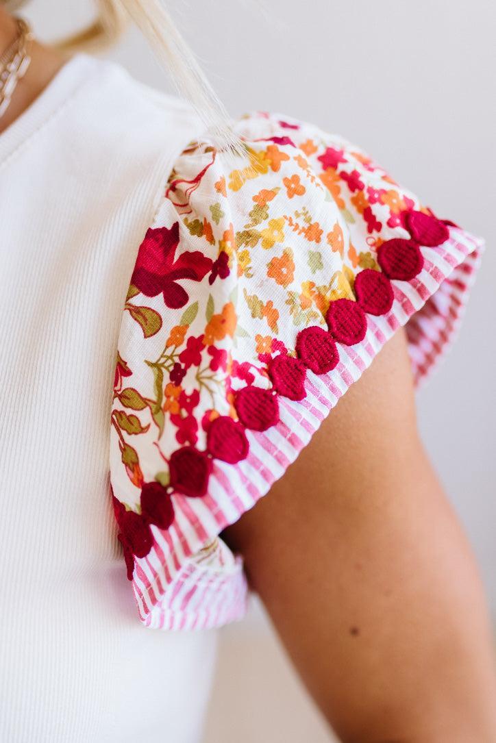 Colorful floral and polka dot fabric draped over a person's shoulder on a light background
