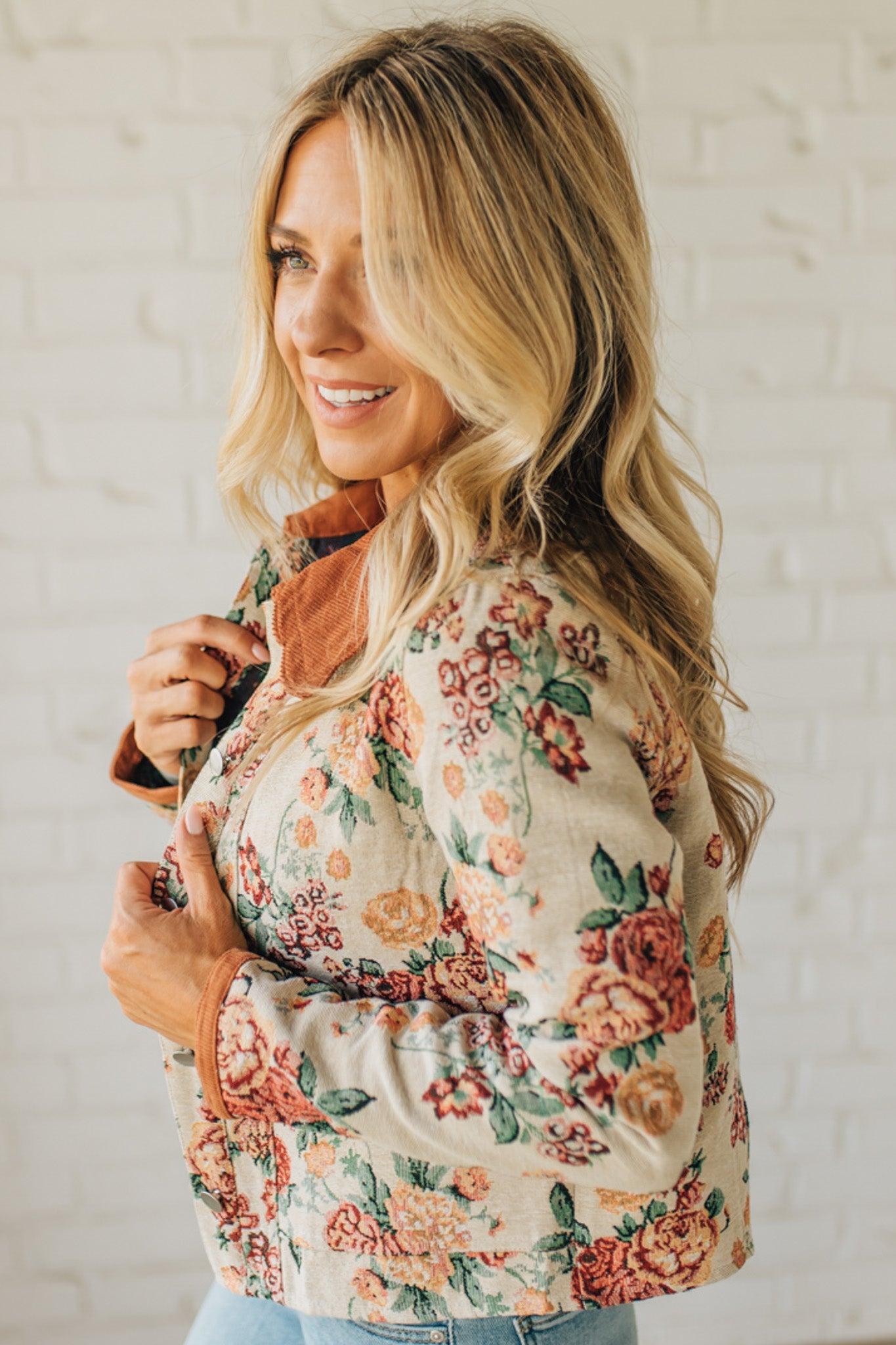 Woman wearing a floral jacket against a white brick wall