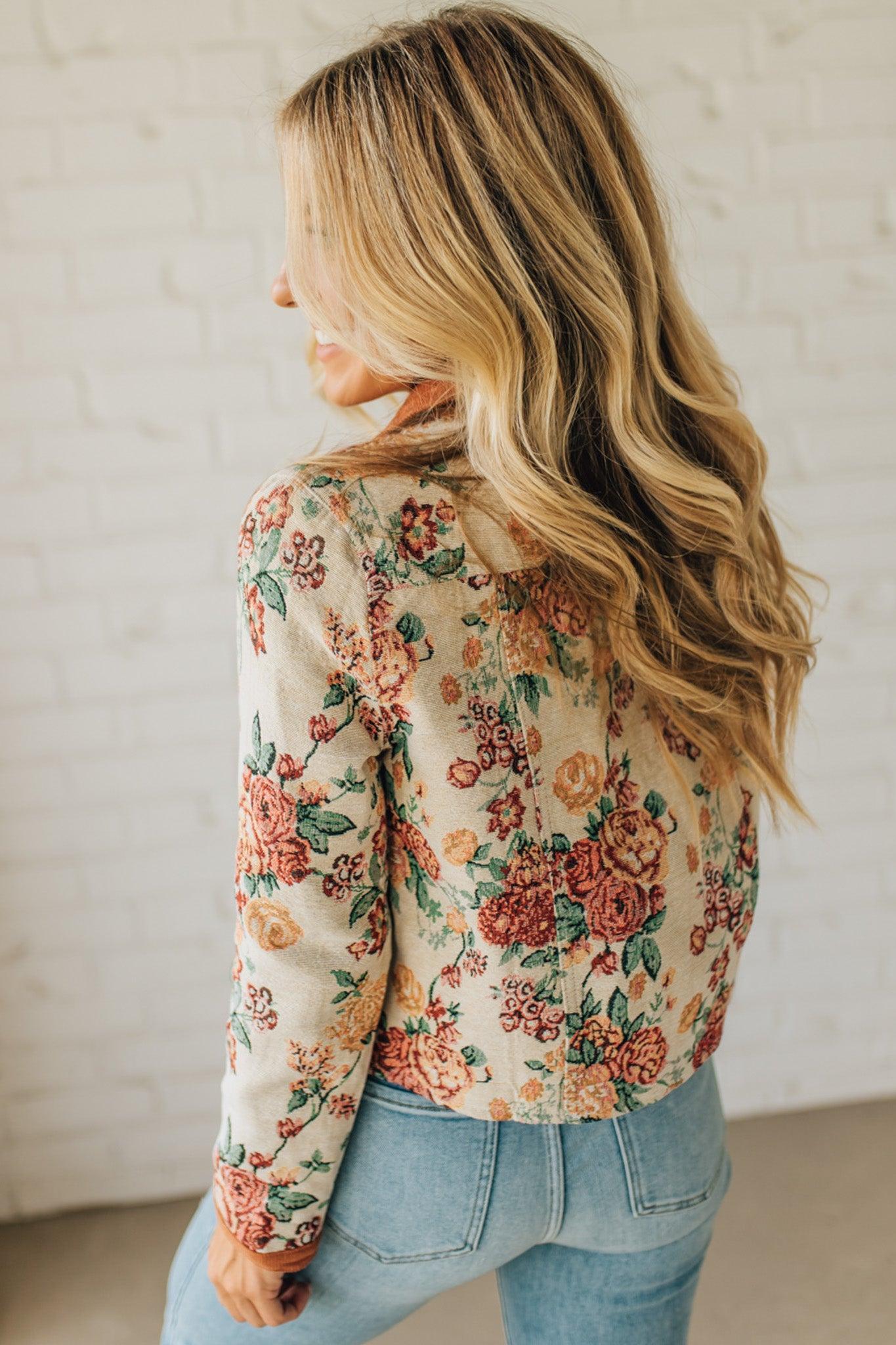 Woman wearing a floral jacket and jeans against a plain background