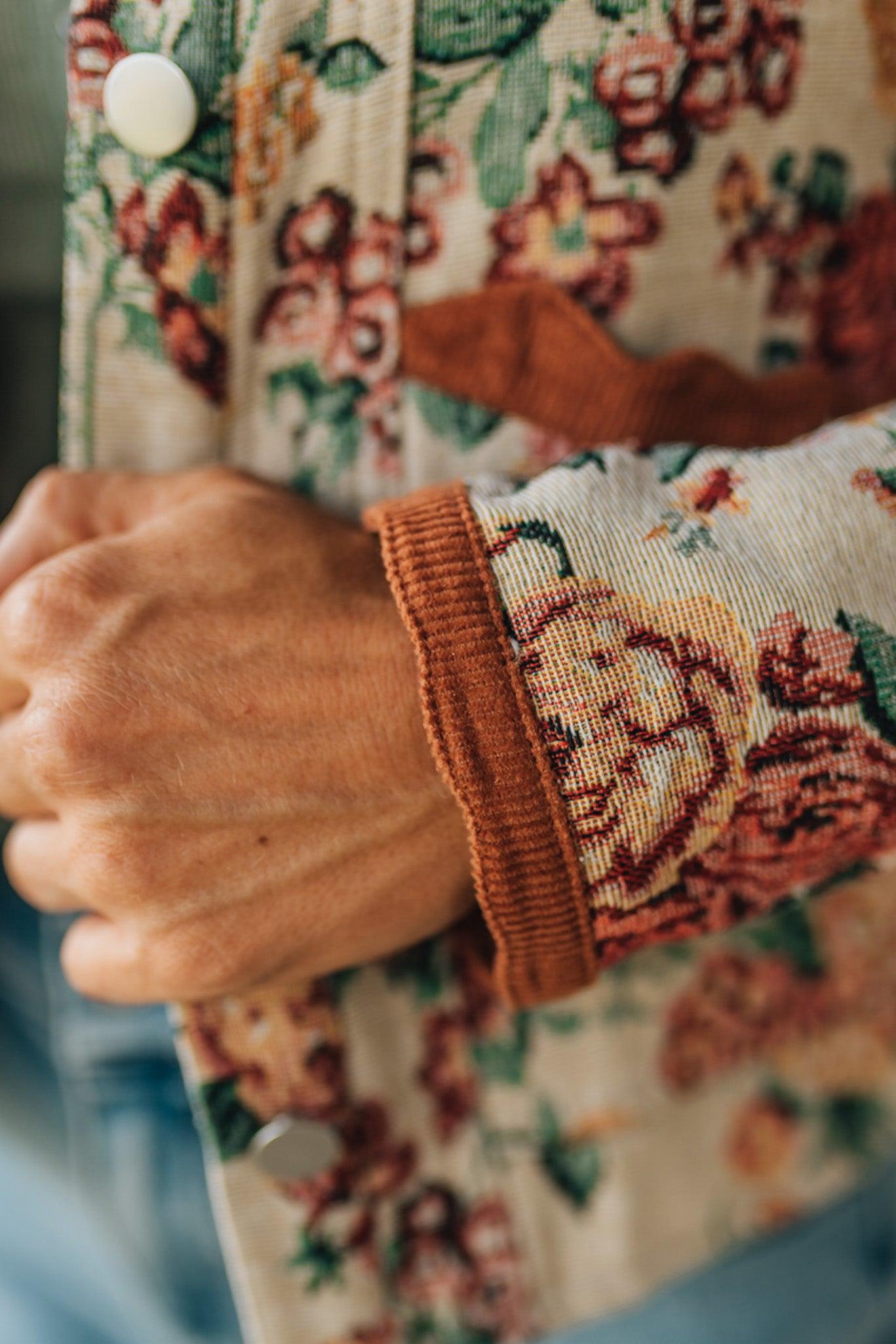 Close-up of a person wearing a floral-patterned jacket with a focus on the sleeve.