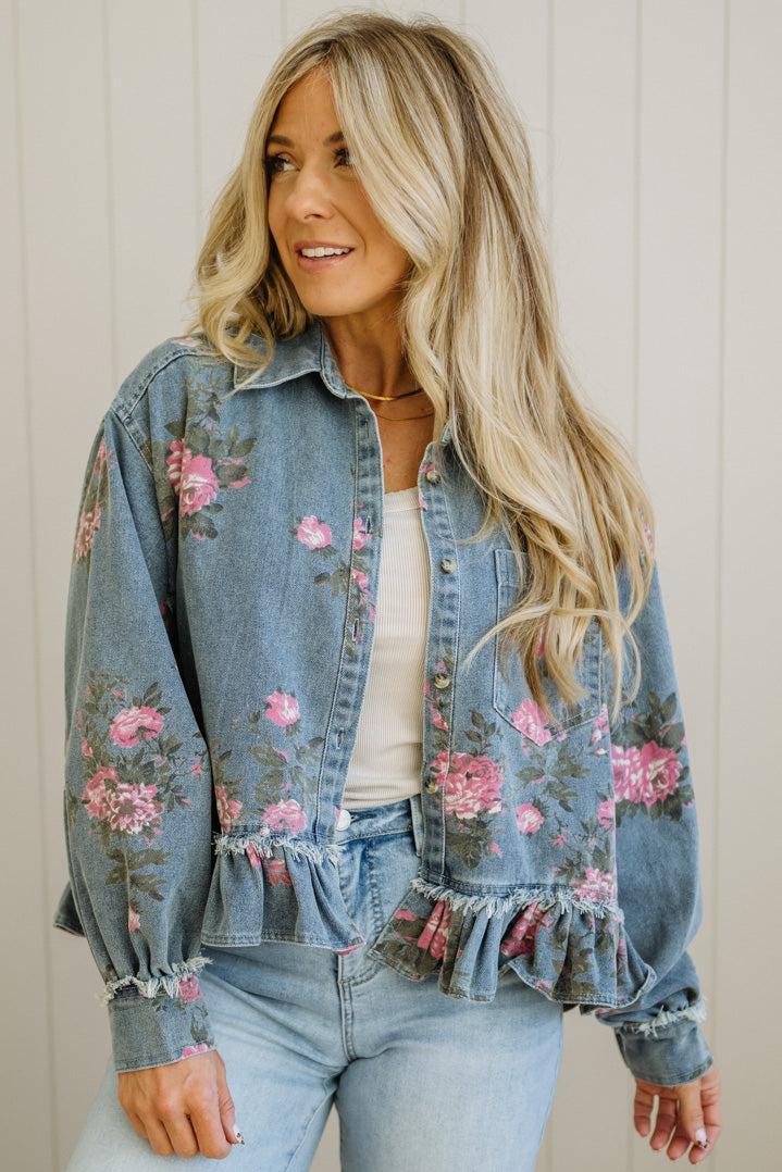 Woman wearing a floral denim jacket with a neutral background