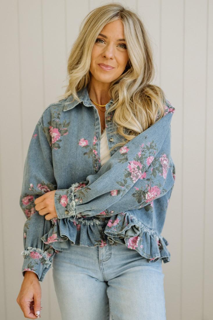 Woman wearing a floral denim jacket with a neutral background