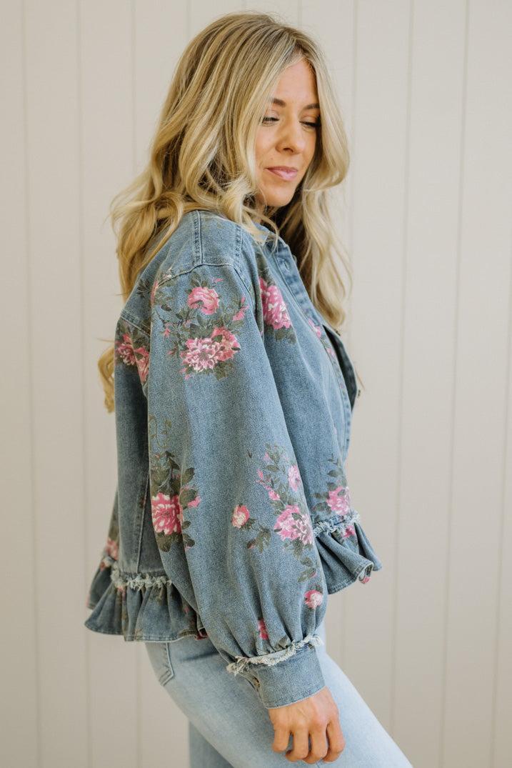 Woman wearing a floral denim jacket against a neutral background