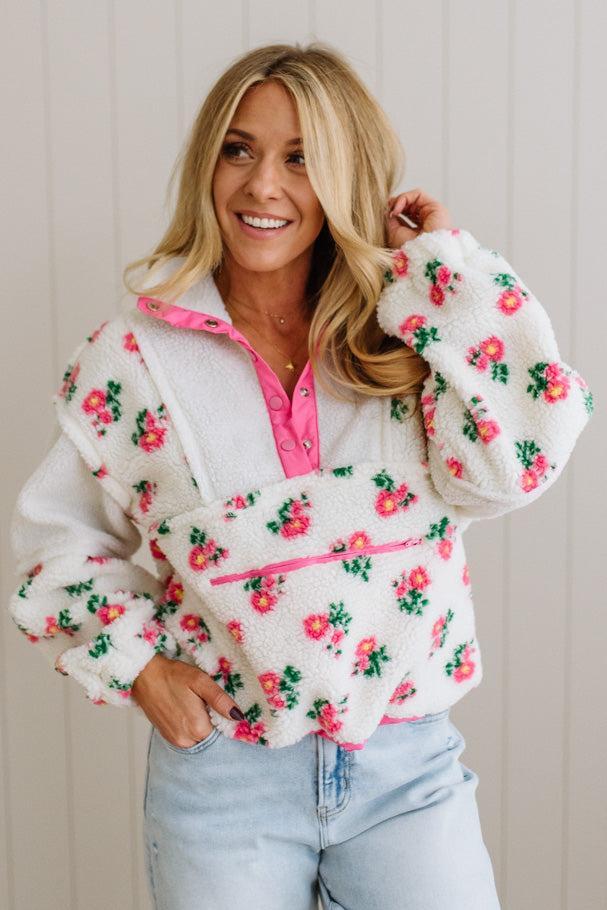 Woman wearing a floral patterned jacket with pink accents against a neutral background