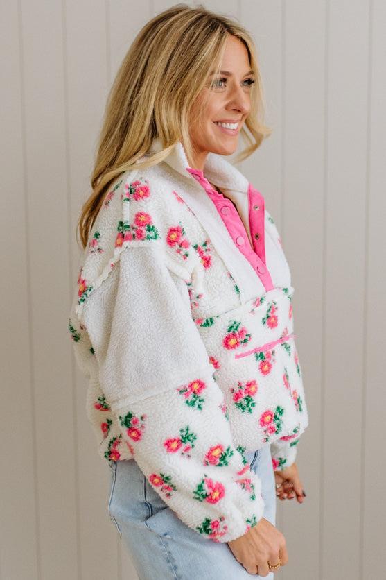 Woman wearing a floral jacket with pink lining against a neutral background