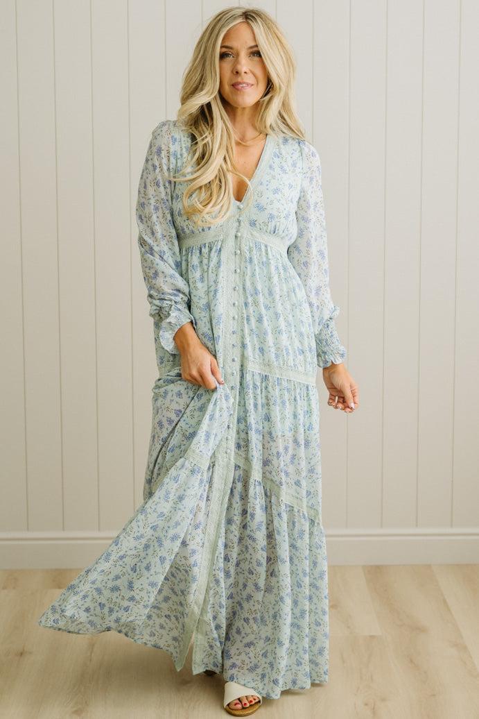 Woman wearing a long floral dress against a plain background