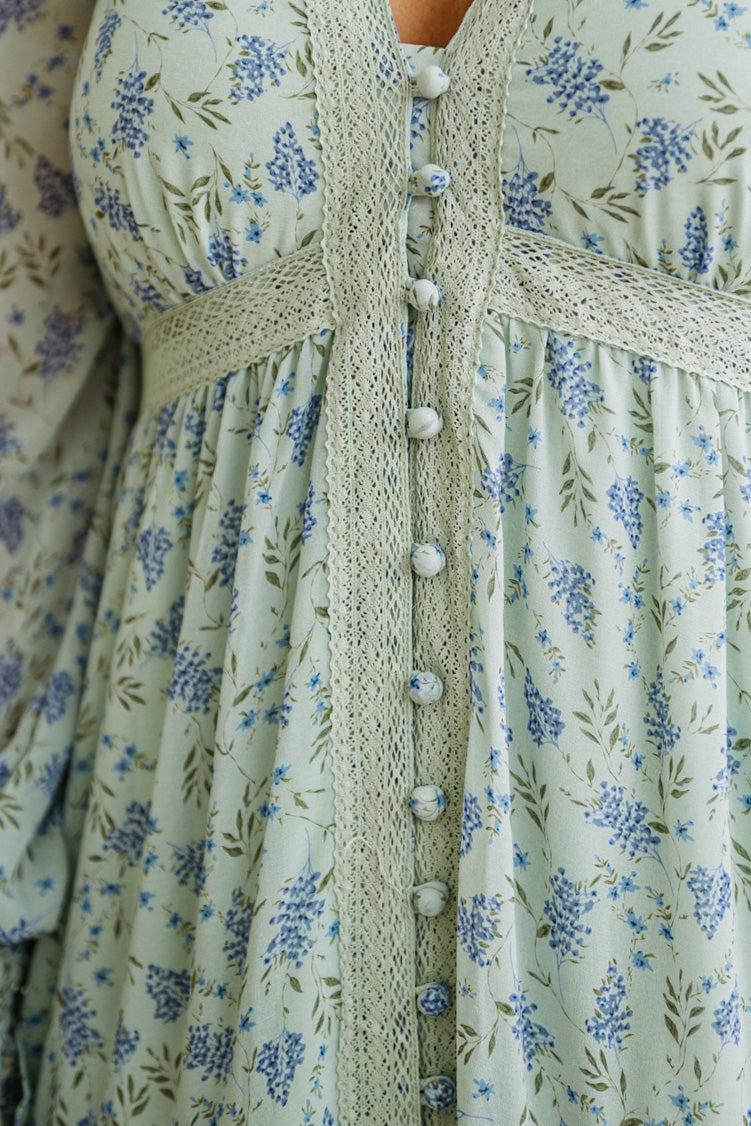 Close-up of a floral dress with a knitted cardigan featuring buttons.