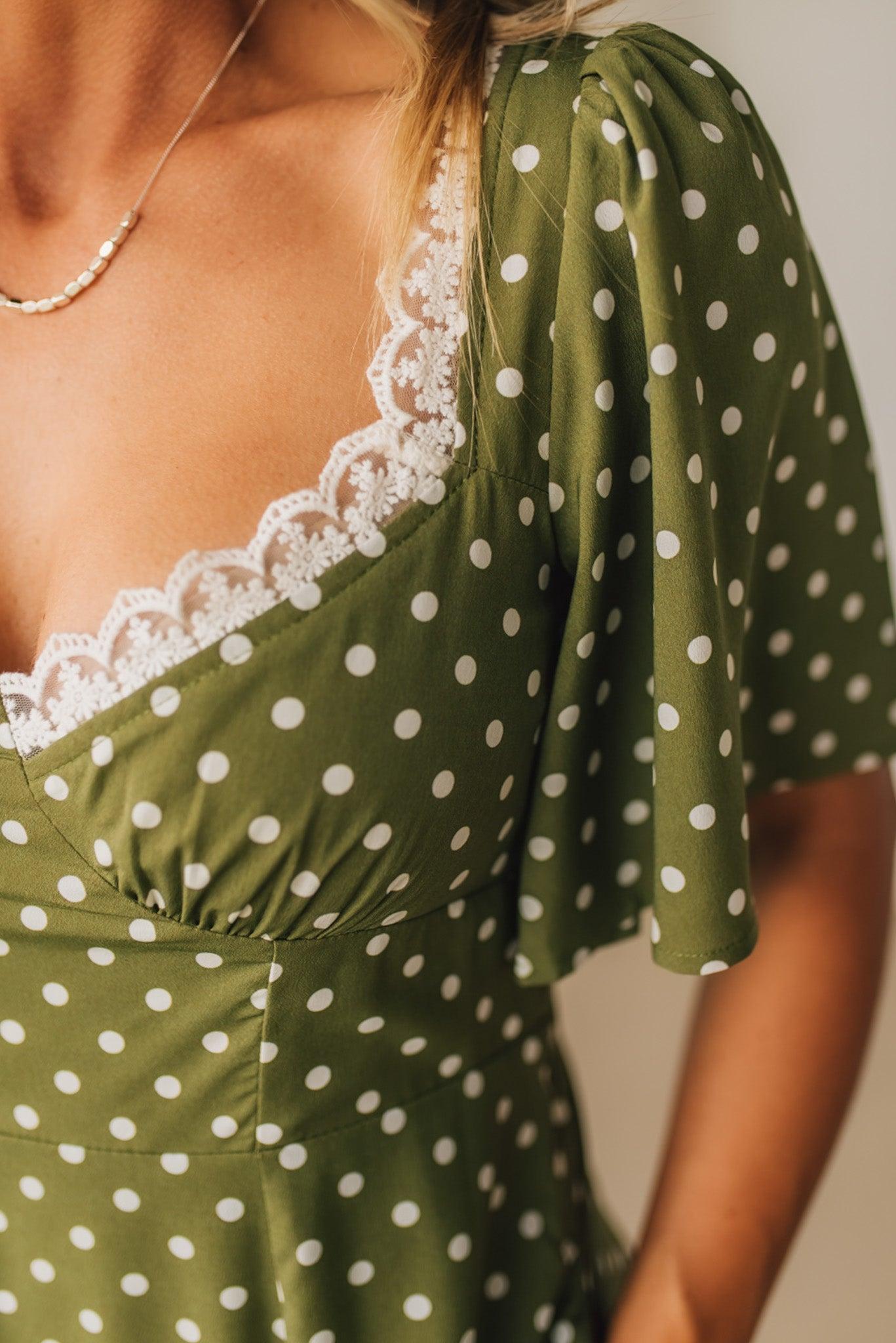 Green polka dot dress with white lace trim on a neutral background