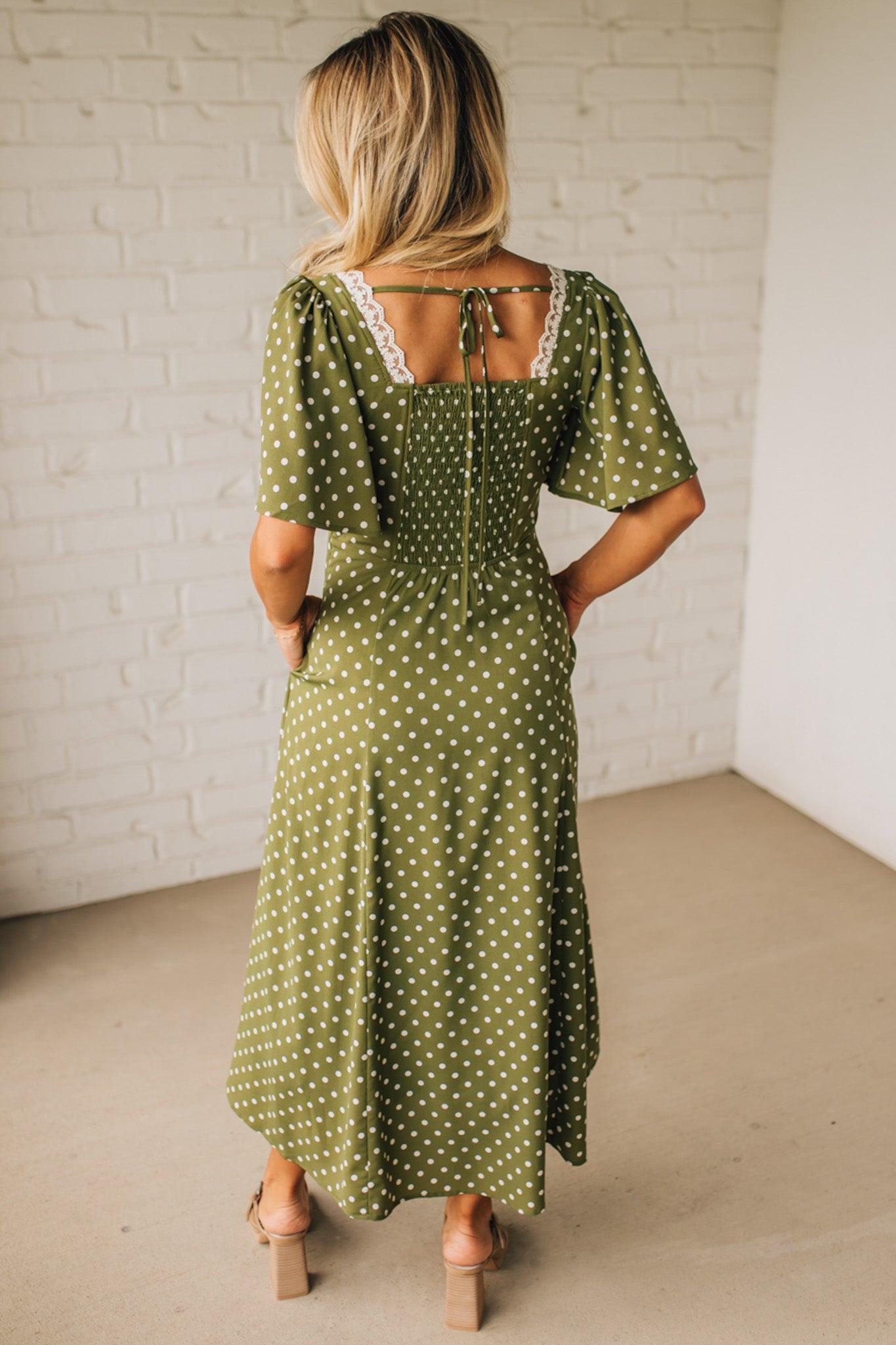 Woman wearing a green polka dot dress in a minimal indoor setting