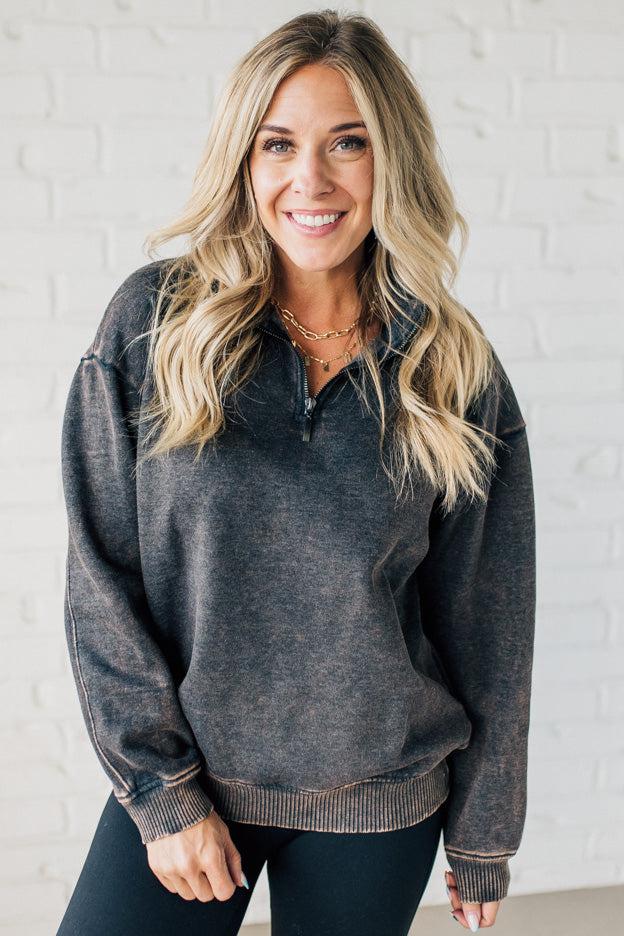 Blonde woman wearing a solid fleece lined sweatshirt with quarter zip henley collar and drop shoulders.