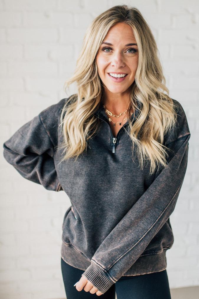 Blonde woman wearing a solid fleece lined sweatshirt with quarter zip henley collar and drop shoulders.