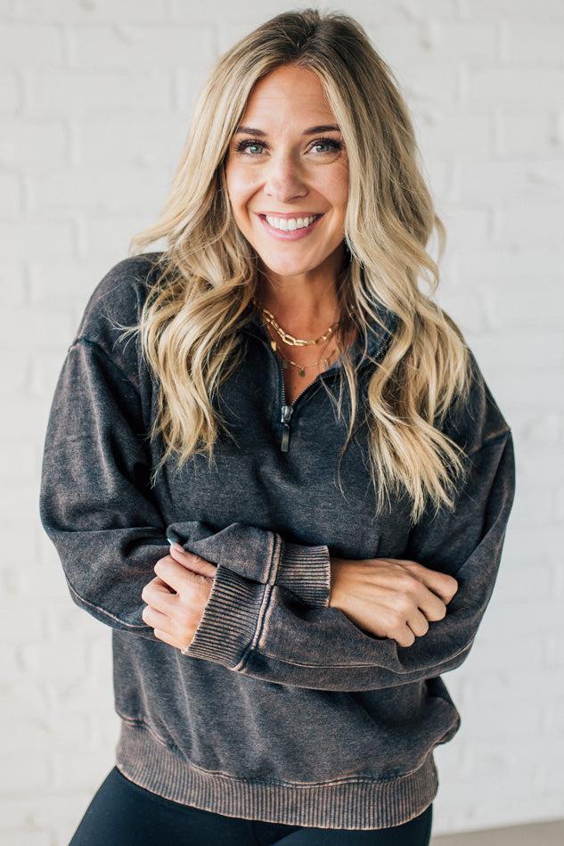 Blonde woman wearing a solid fleece lined sweatshirt with quarter zip henley collar and drop shoulders.