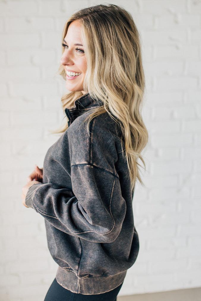 Blonde woman wearing a solid fleece lined sweatshirt with quarter zip henley collar and drop shoulders.