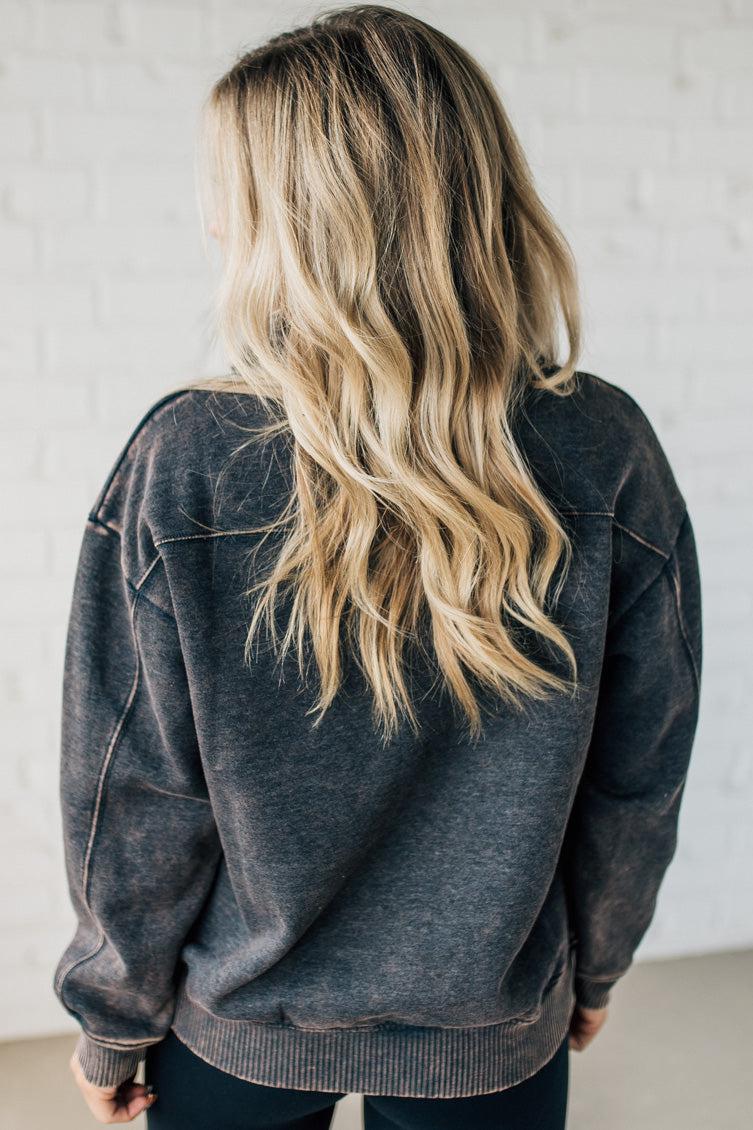 Blonde woman wearing a solid fleece lined sweatshirt with quarter zip henley collar and drop shoulders.