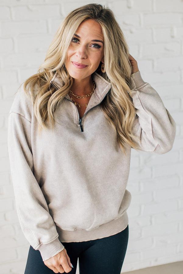 Blonde woman wearing a solid fleece lined sweatshirt with quarter zip henley collar and drop shoulders.