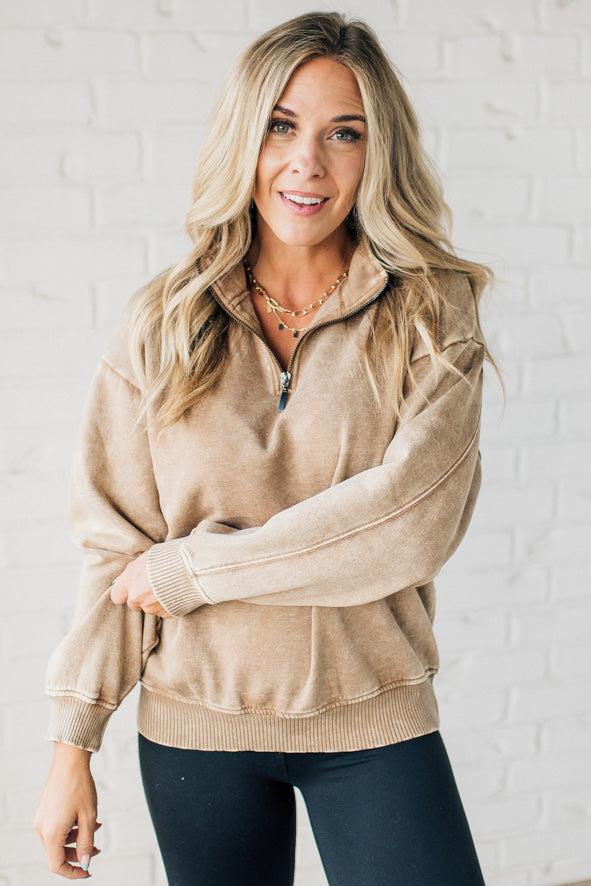 Blonde woman wearing a solid fleece lined sweatshirt with quarter zip henley collar and drop shoulders.