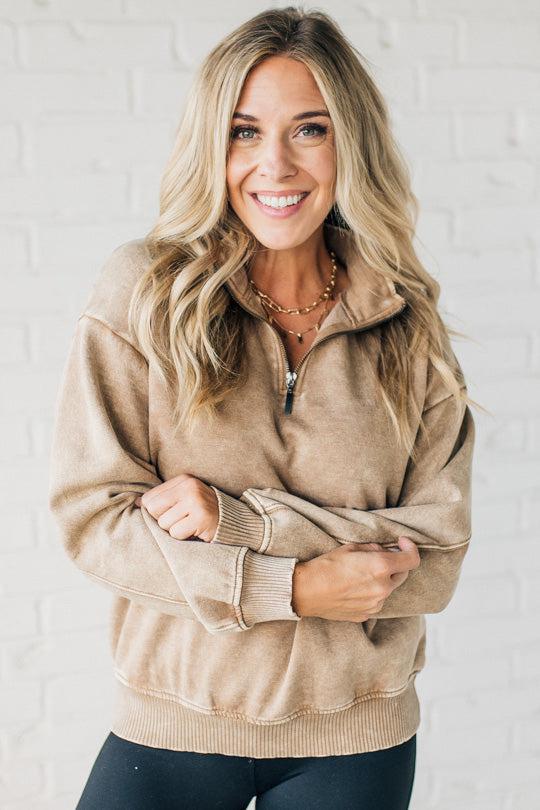 Blonde woman wearing a solid fleece lined sweatshirt with quarter zip henley collar and drop shoulders.