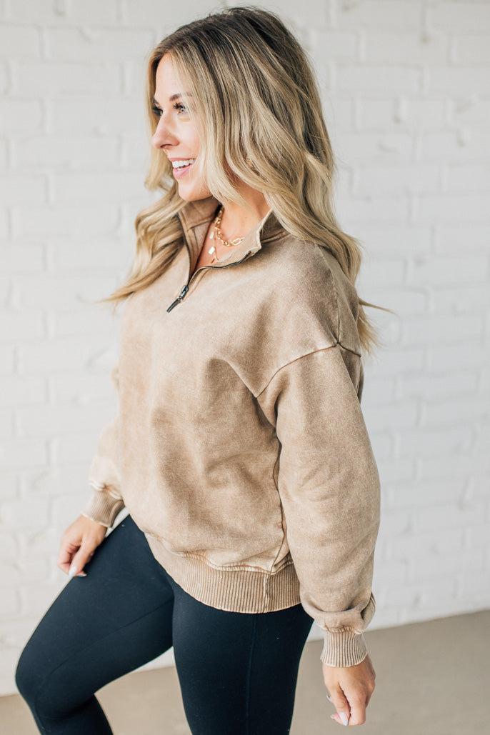 Blonde woman wearing a solid fleece lined sweatshirt with quarter zip henley collar and drop shoulders.