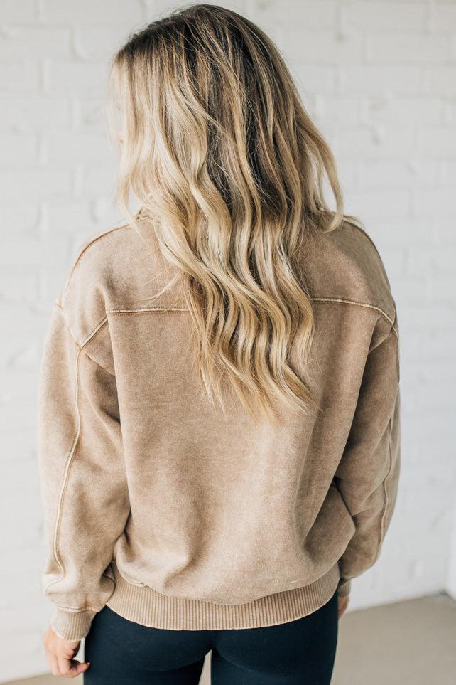 Blonde woman wearing a solid fleece lined sweatshirt with quarter zip henley collar and drop shoulders.