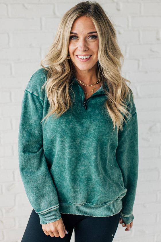 Blonde woman wearing a solid fleece lined sweatshirt with quarter zip henley collar and drop shoulders.