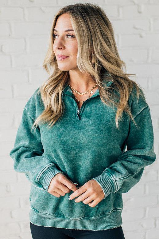 Blonde woman wearing a solid fleece lined sweatshirt with quarter zip henley collar and drop shoulders.