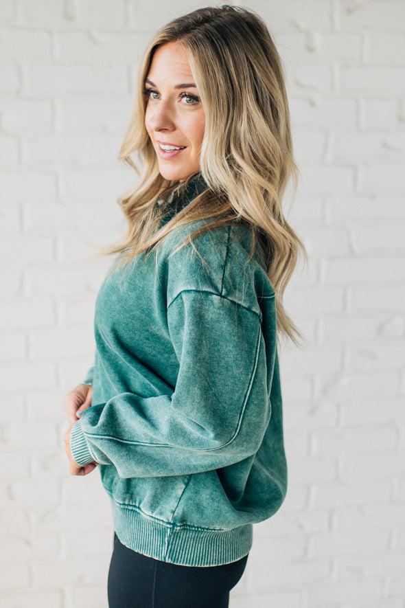 Blonde woman wearing a solid fleece lined sweatshirt with quarter zip henley collar and drop shoulders.