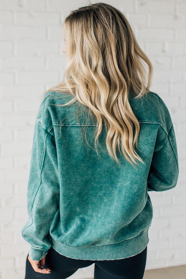 Blonde woman wearing a solid fleece lined sweatshirt with quarter zip henley collar and drop shoulders.