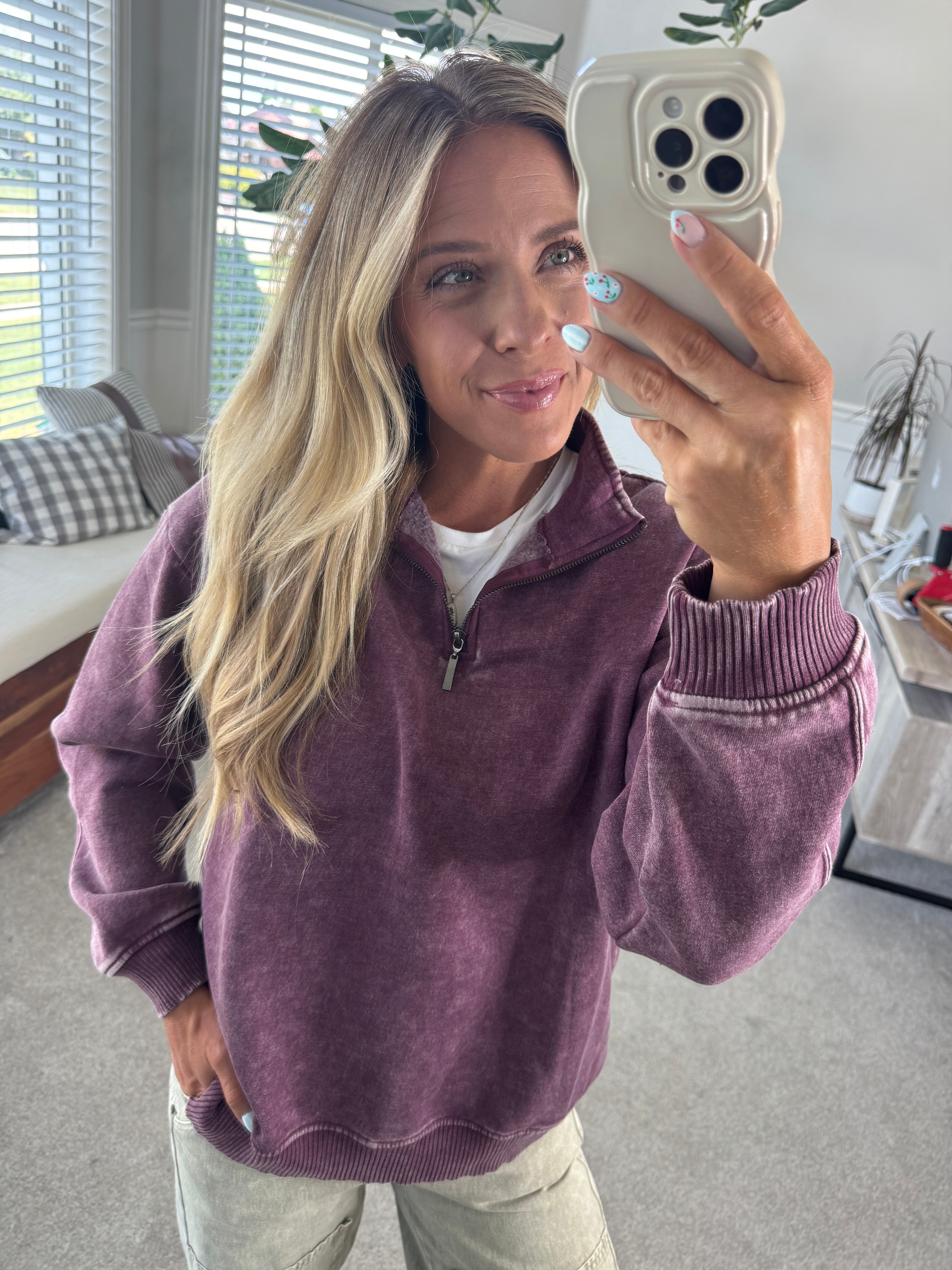 Blonde woman wearing a solid fleece lined sweatshirt with quarter zip henley collar and drop shoulders.