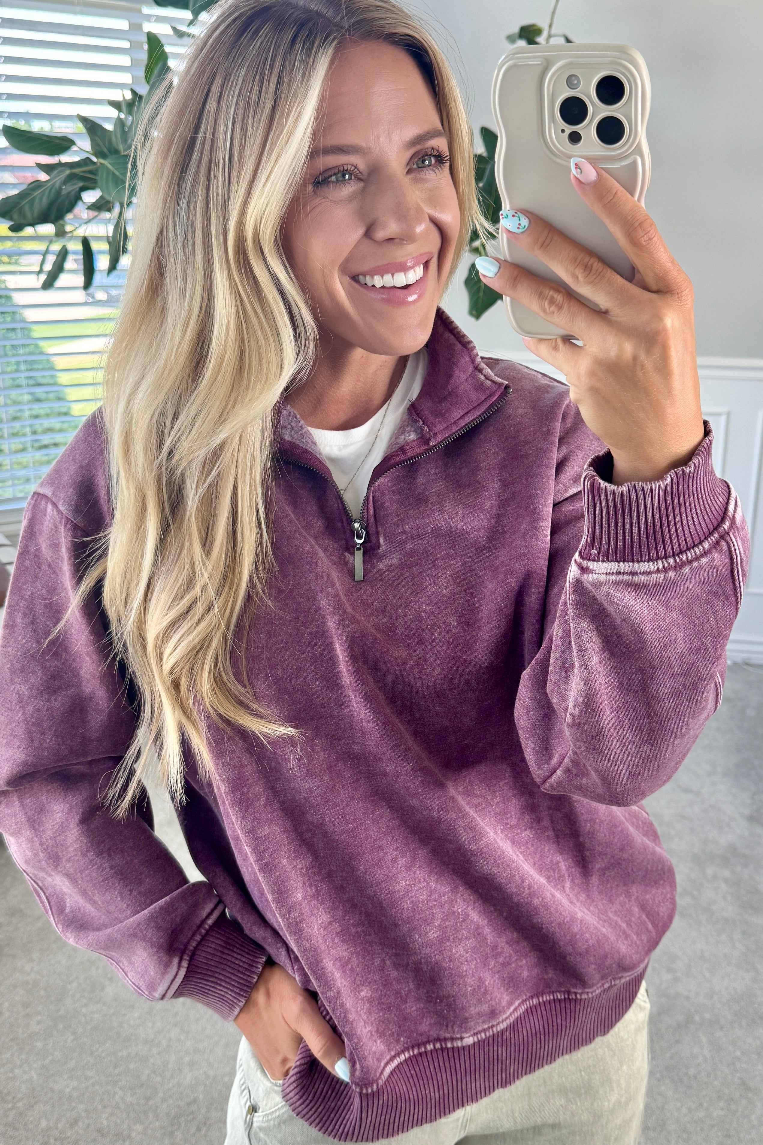 Blonde woman wearing a solid fleece lined sweatshirt with quarter zip henley collar and drop shoulders.