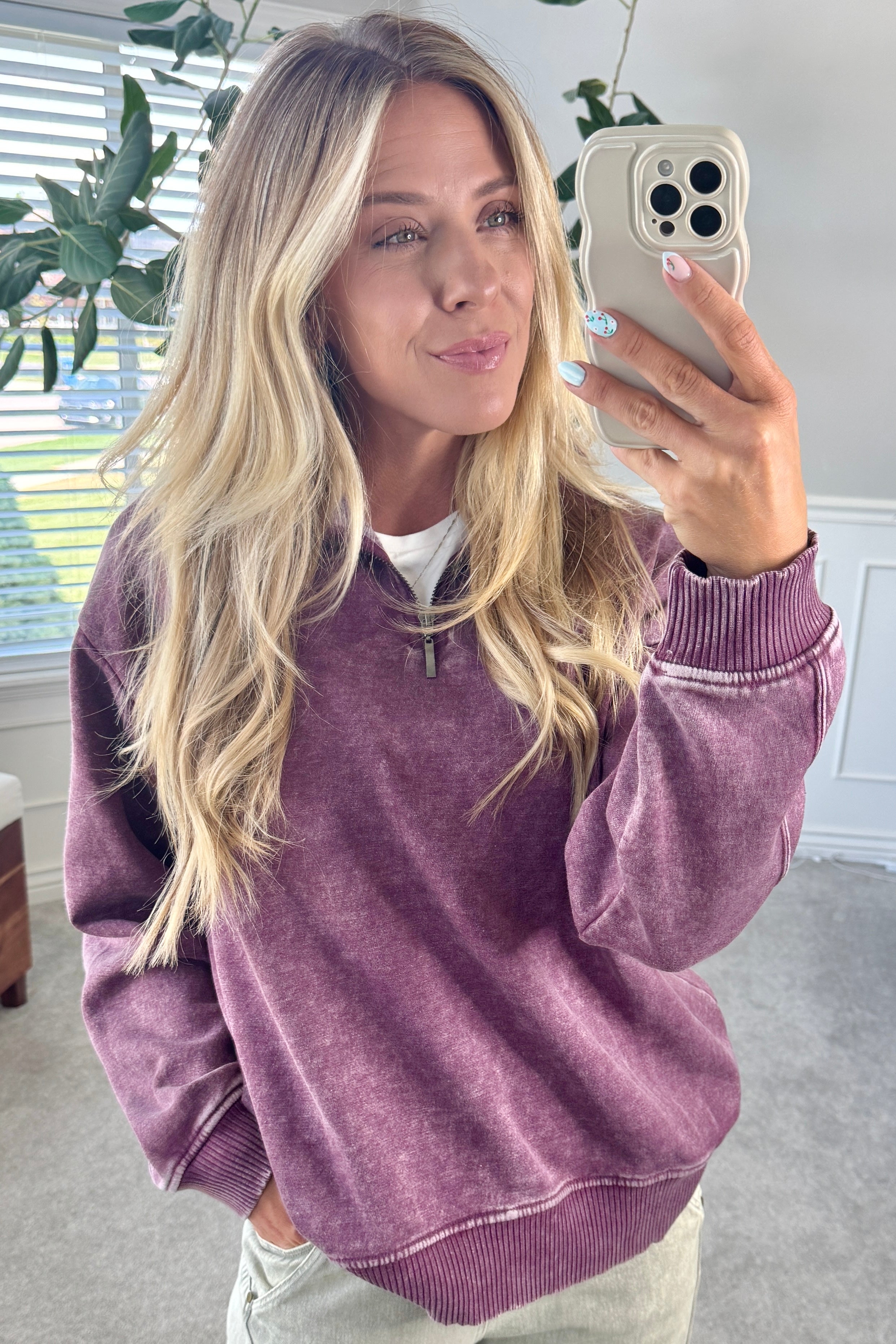 Blonde woman wearing a solid fleece lined sweatshirt with quarter zip henley collar and drop shoulders.