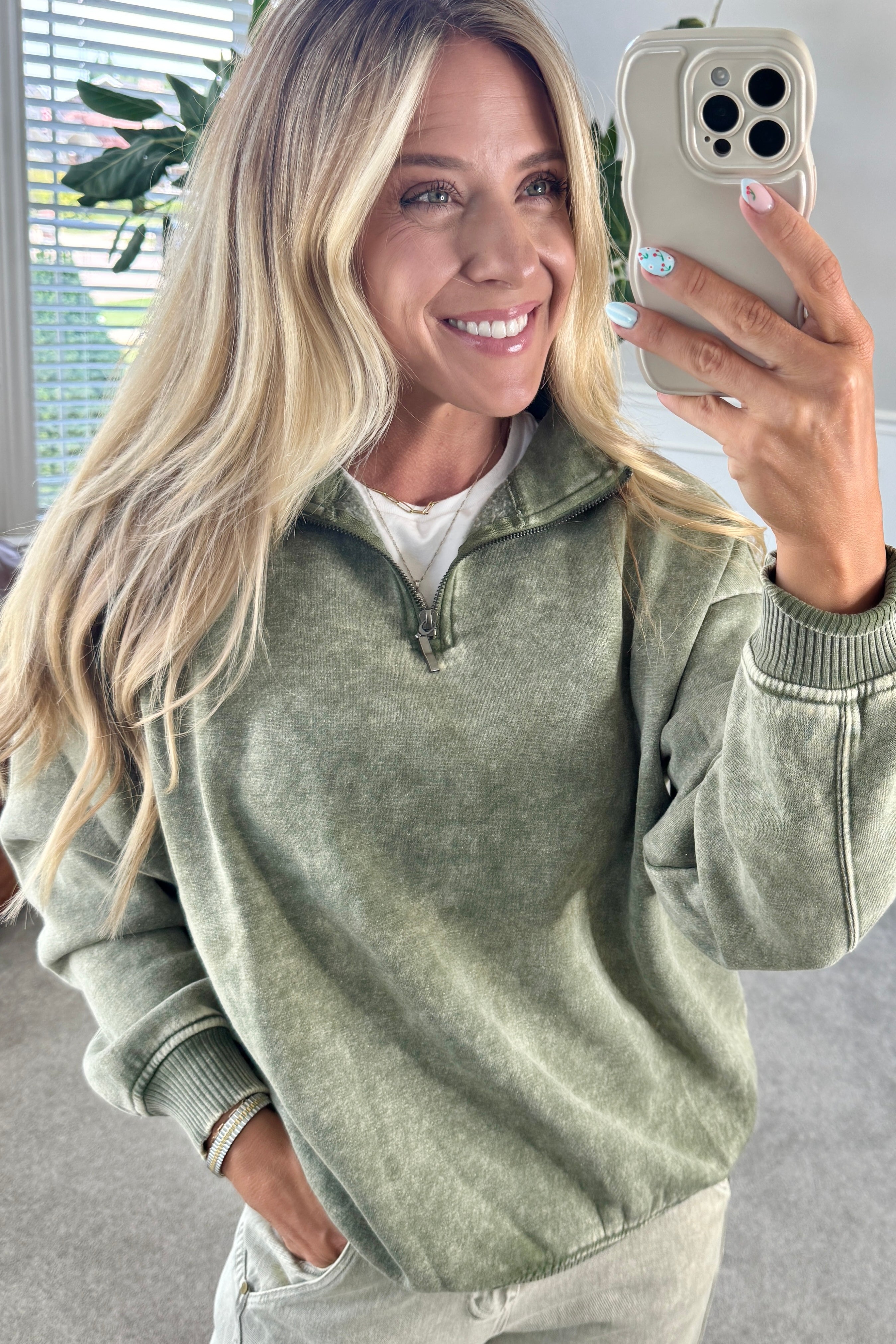 Blonde woman wearing a solid fleece lined sweatshirt with quarter zip henley collar and drop shoulders.