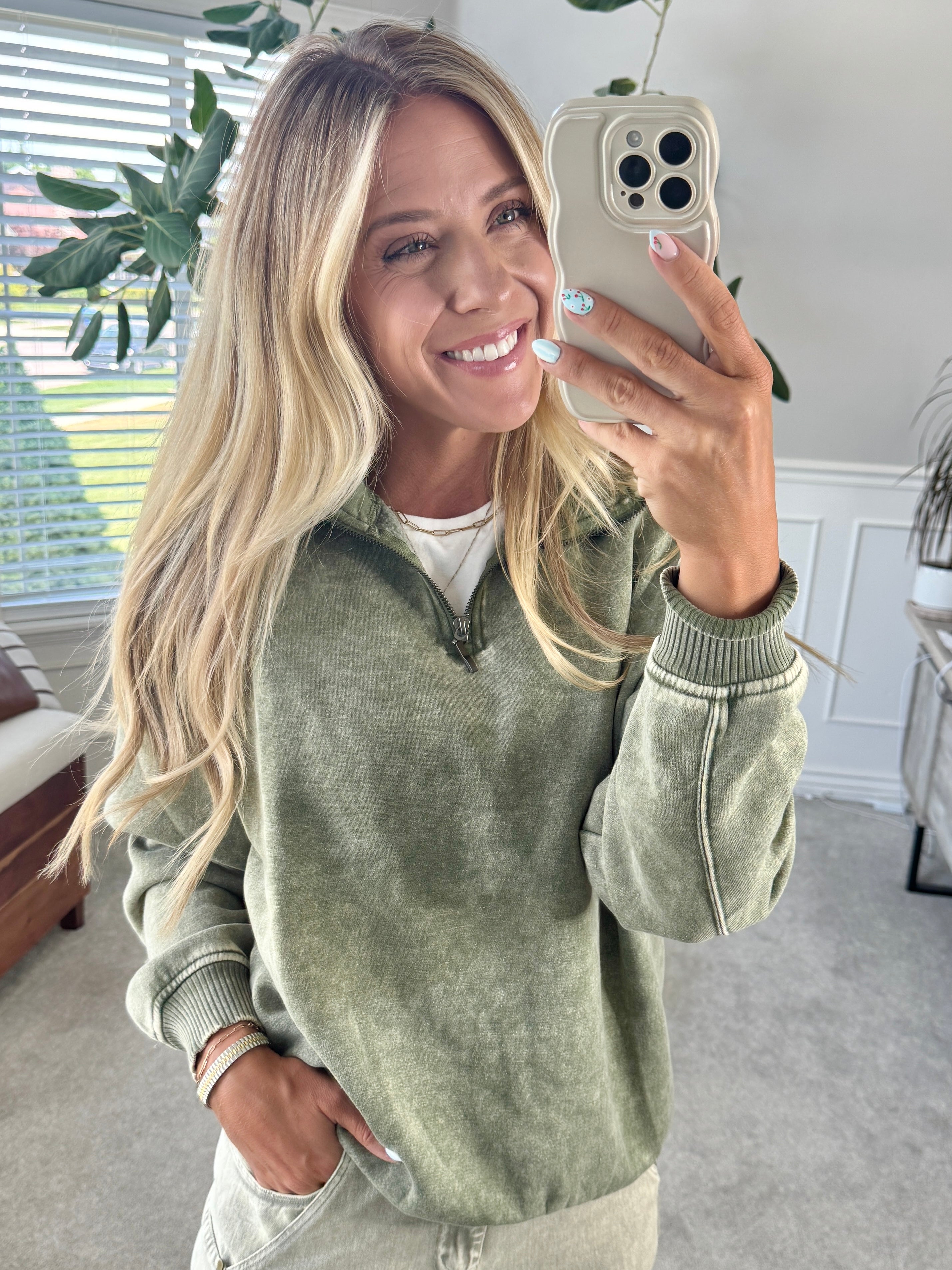 Blonde woman wearing a solid fleece lined sweatshirt with quarter zip henley collar and drop shoulders.