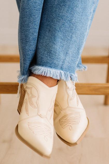 Finged jeans close up with cream embroidered western inspired slip on heel boots.