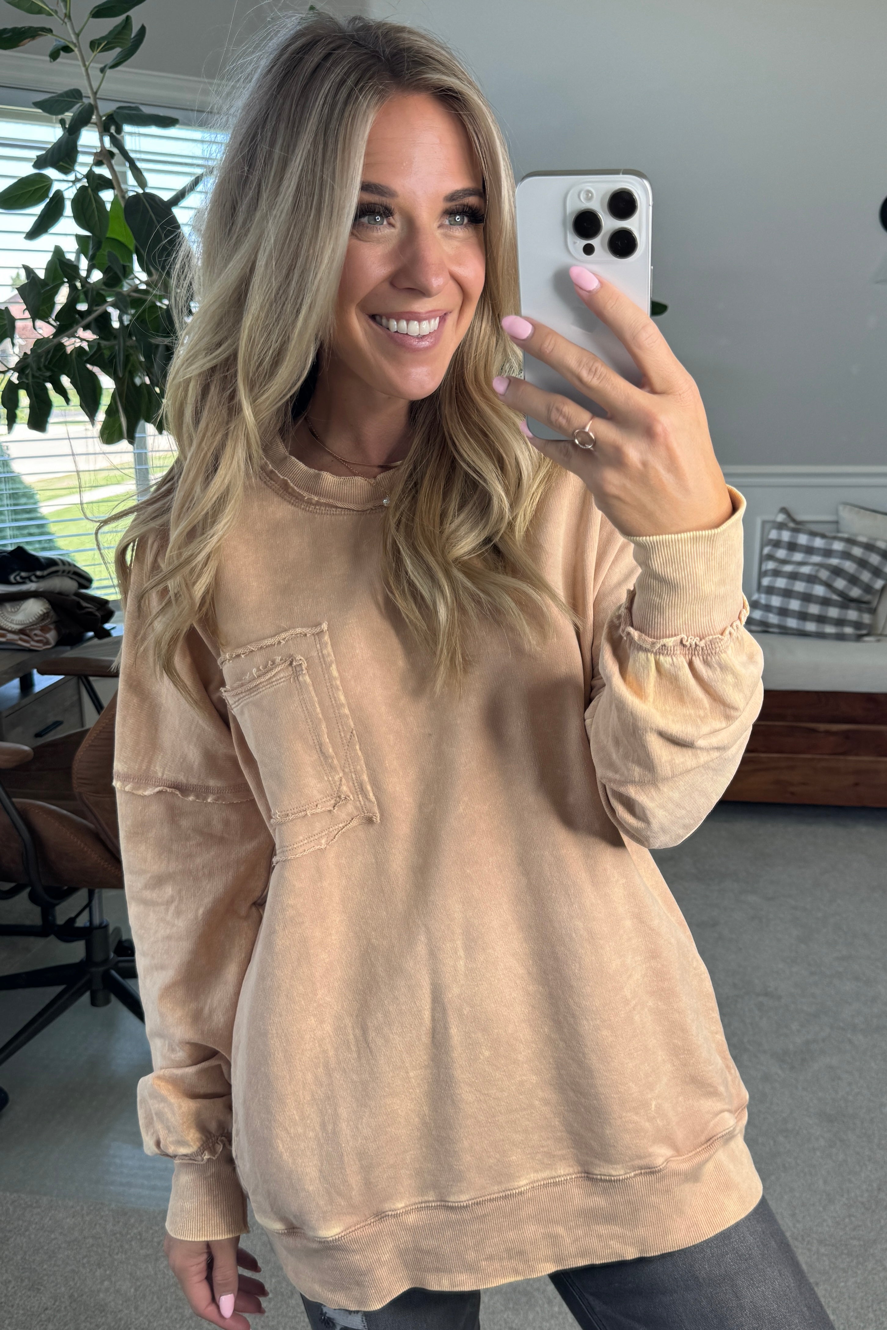 Blonde woman wearing a boyfriend fit drop shoulder sweatshirt pullover, with front pocket accent, exposed raw seams, and all over acid wash detail.