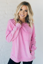 Blonde woman wearing a boyfriend fit drop shoulder sweatshirt pullover, with front pocket accent, exposed raw seams, and all over acid wash detail.