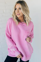 Blonde woman wearing a boyfriend fit drop shoulder sweatshirt pullover, with front pocket accent, exposed raw seams, and all over acid wash detail.