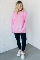 Blonde woman wearing a boyfriend fit drop shoulder sweatshirt pullover, with front pocket accent, exposed raw seams, and all over acid wash detail.